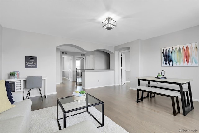 living room with arched walkways, wood finished floors, and baseboards