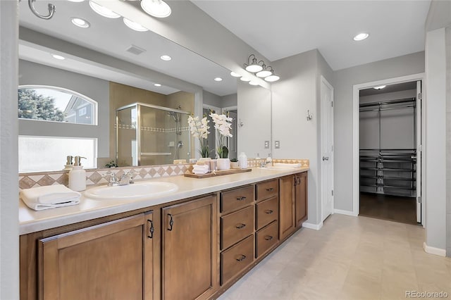 bathroom with a stall shower, double vanity, recessed lighting, baseboards, and decorative backsplash