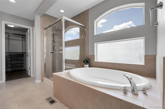 full bath featuring a stall shower, a spacious closet, and a garden tub