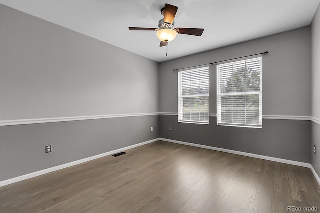 empty room featuring a ceiling fan, wood finished floors, and baseboards