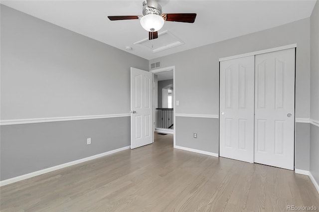 unfurnished bedroom with wood finished floors, a closet, baseboards, and a ceiling fan