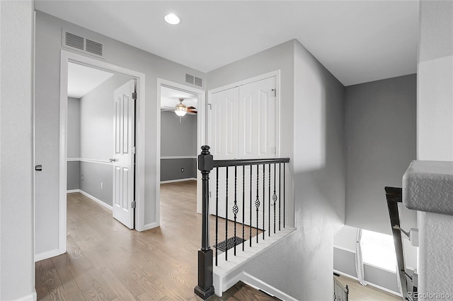 hall with an upstairs landing, wood finished floors, baseboards, and recessed lighting