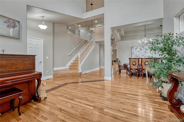 living area with wood finished floors, a towering ceiling, a chandelier, stairway, and baseboards