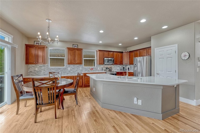 kitchen featuring stainless steel appliances, a sink, decorative backsplash, light wood finished floors, and recessed lighting