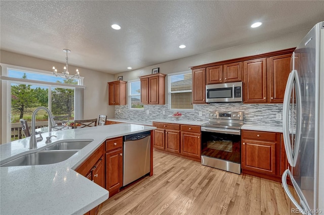 kitchen with stainless steel appliances, a sink, light wood-type flooring, a chandelier, and tasteful backsplash