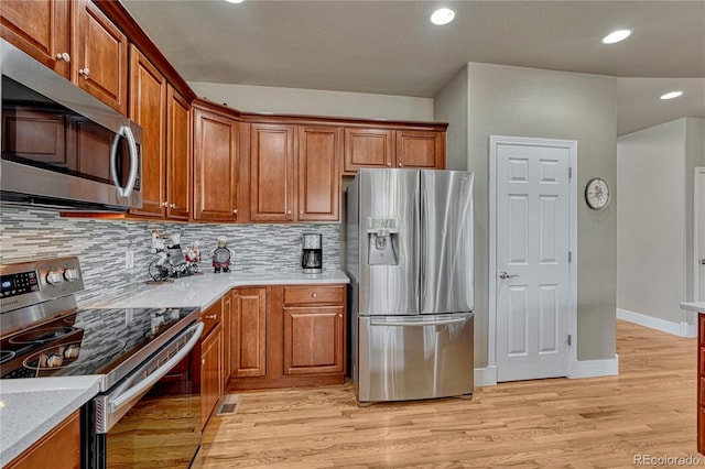 kitchen with appliances with stainless steel finishes, tasteful backsplash, brown cabinetry, light wood-type flooring, and recessed lighting