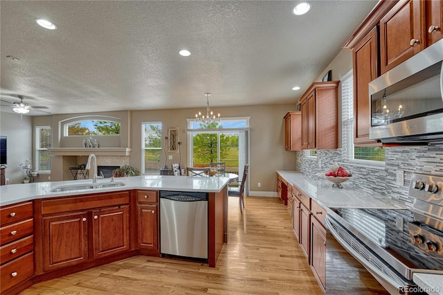 kitchen featuring appliances with stainless steel finishes, a sink, a fireplace, light countertops, and a textured ceiling
