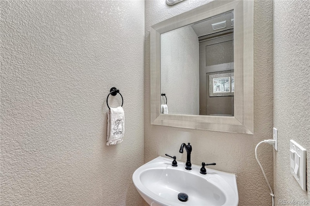 bathroom featuring a sink and a textured wall