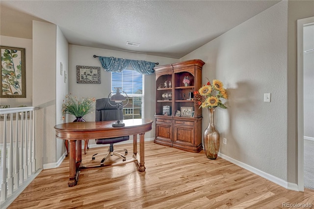 office area with light wood finished floors, baseboards, a textured ceiling, and a textured wall