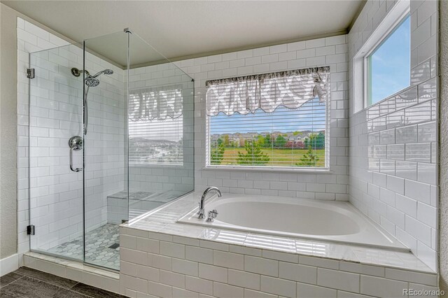 bathroom with healthy amount of natural light, a stall shower, and a bath