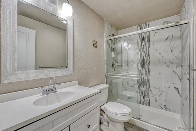 full bathroom featuring a textured wall, toilet, a shower stall, vanity, and a textured ceiling