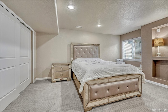 bedroom with light colored carpet, a textured ceiling, baseboards, and recessed lighting