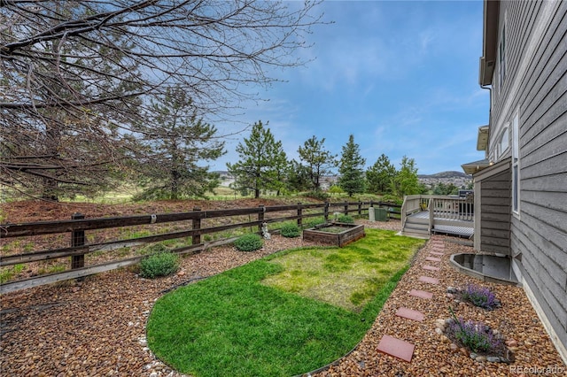 view of yard featuring fence, a garden, and a wooden deck