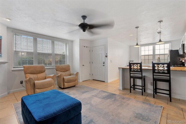 living room with ceiling fan, light tile patterned flooring, and a healthy amount of sunlight