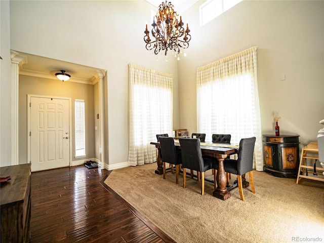 dining space featuring a notable chandelier, crown molding, a high ceiling, wood finished floors, and baseboards