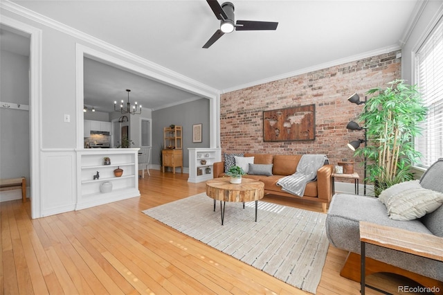 living room featuring ornamental molding, brick wall, hardwood / wood-style floors, and ceiling fan with notable chandelier