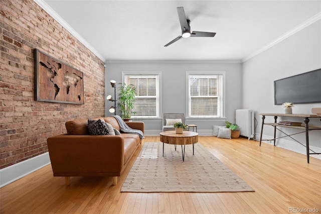 living area with baseboards, radiator, hardwood / wood-style flooring, brick wall, and ornamental molding