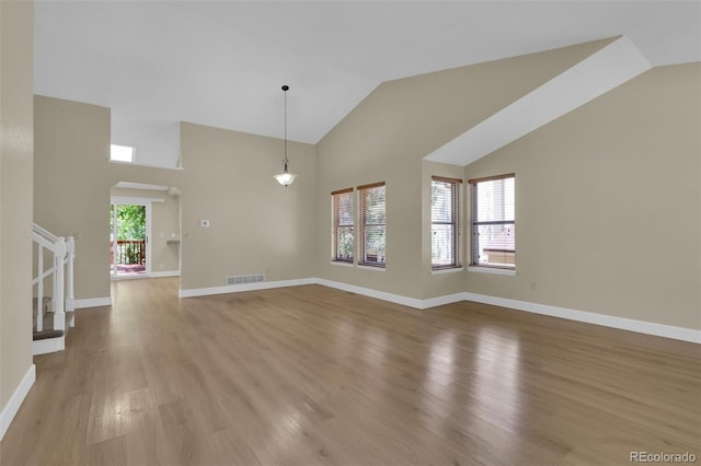 14463 E Wagon Trail Pl, Aurora, CO 80015 - unfurnished living room featuring light wood-style flooring, arched walkways, and high vaulted ceiling
