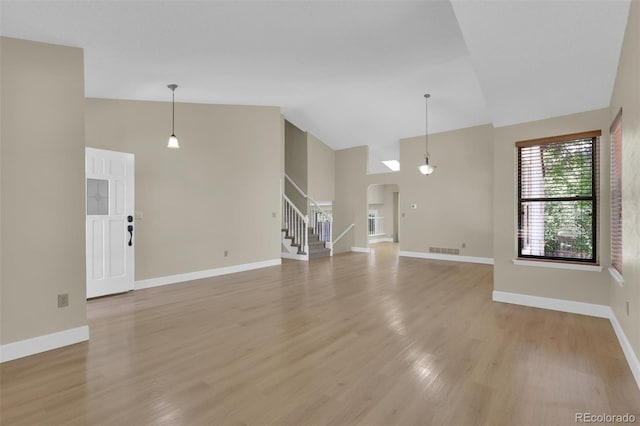 14463 E Wagon Trail Pl, Aurora, CO 80015 - unfurnished living room featuring arched walkways, stairway, high vaulted ceiling, and light wood finished floors
