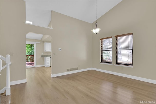 14463 E Wagon Trail Pl, Aurora, CO 80015 - unfurnished room with high vaulted ceiling, light wood-style floors, and arched walkways