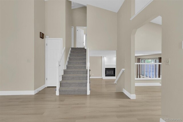 14463 E Wagon Trail Pl, Aurora, CO 80015 - entryway featuring a towering ceiling, light wood finished floors, a glass covered fireplace, and stairs