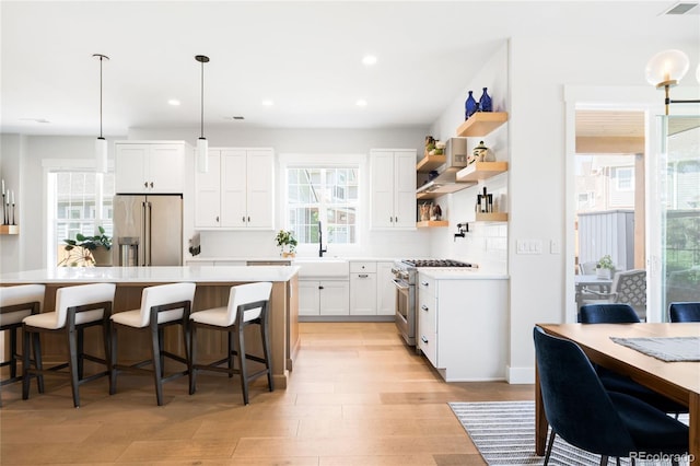 8357 W 68th Ln, Arvada, CO 80004 - kitchen with appliances with stainless steel finishes, decorative backsplash, a kitchen breakfast bar, plenty of natural light, and recessed lighting