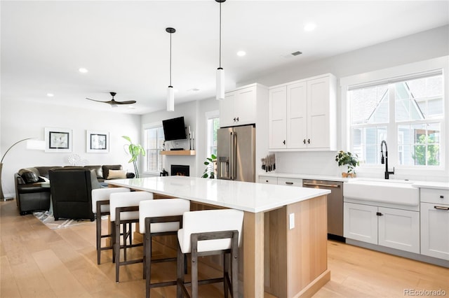 8357 W 68th Ln, Arvada, CO 80004 - kitchen featuring stainless steel appliances, a sink, a fireplace, healthy amount of natural light, and recessed lighting