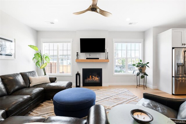 8357 W 68th Ln, Arvada, CO 80004 - living room featuring healthy amount of natural light, ceiling fan, light wood-style flooring, and baseboards
