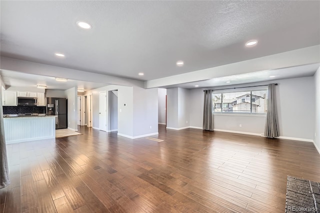 unfurnished living room with dark wood-style flooring, baseboards, and recessed lighting