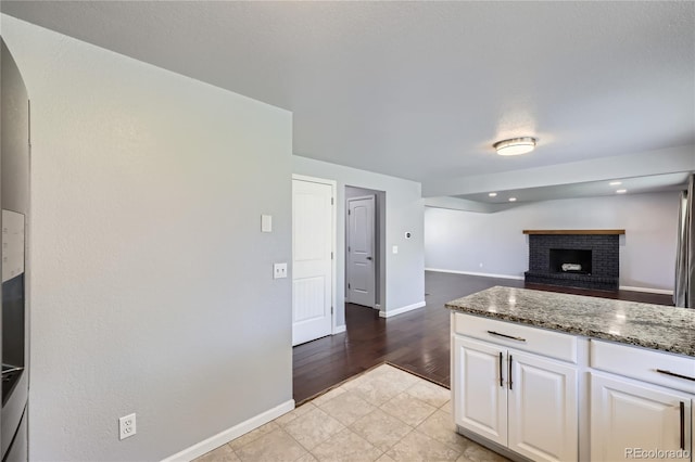 kitchen featuring white cabinets, arched walkways, baseboards, and dark stone counters