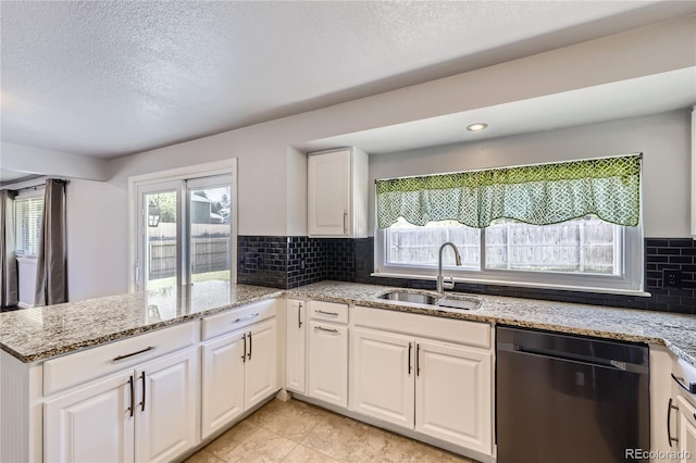 kitchen featuring white cabinets, a sink, dishwasher, a textured ceiling, and a peninsula