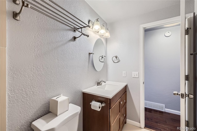 bathroom with visible vents, wood finished floors, vanity, baseboards, and toilet
