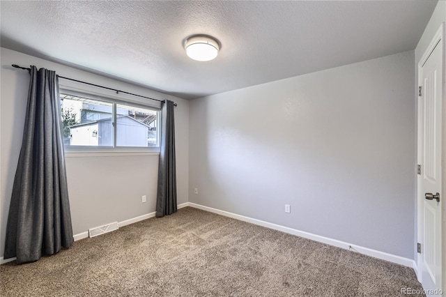 carpeted empty room with visible vents, a textured ceiling, and baseboards