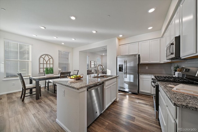 kitchen with stainless steel appliances, a center island with sink, white cabinetry, and sink