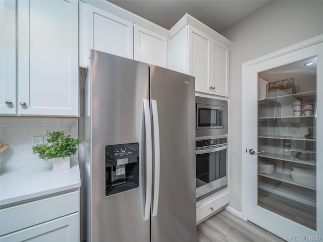 kitchen featuring white cabinetry, backsplash, light hardwood / wood-style flooring, and appliances with stainless steel finishes