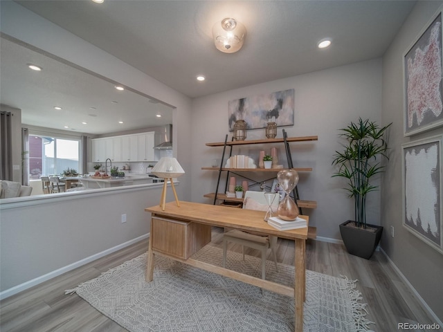 office with sink and light hardwood / wood-style flooring