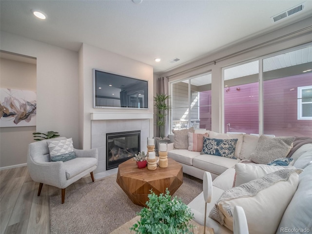 living room featuring plenty of natural light, a tile fireplace, and light hardwood / wood-style flooring