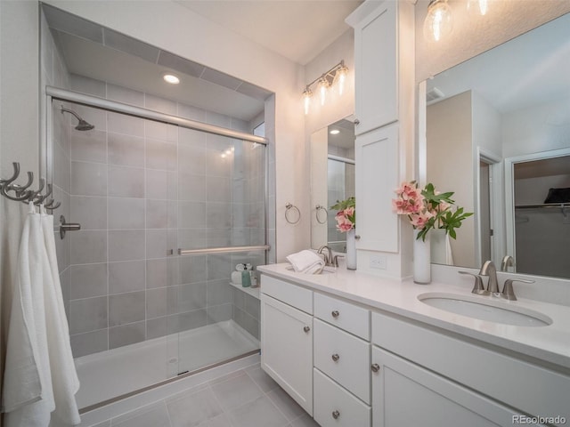 bathroom with a shower with door, vanity, and tile patterned floors