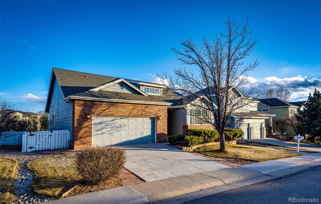 view of front of home featuring brick siding, concrete driveway, a garage, and fence