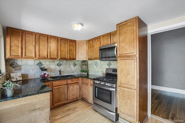 2415 Chase St, Edgewater, CO 80214 - kitchen with stainless steel appliances, a sink, brown cabinetry, light wood-style flooring, and tasteful backsplash