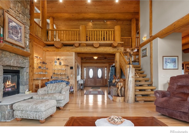 1000 N County Road 33, Como, CO 80432 - living room featuring wood-type flooring, a stone fireplace, a high ceiling, stairway, and rustic walls