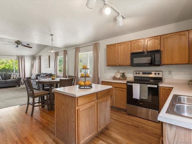 12555 Eastlake Dr, Thornton, CO 80241 - kitchen with black microwave, stainless steel range with electric cooktop, open floor plan, light countertops, and vaulted ceiling