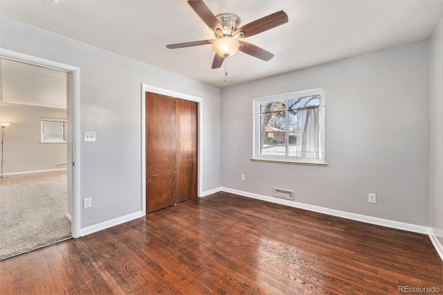 unfurnished bedroom featuring dark hardwood / wood-style floors, ceiling fan, and a closet