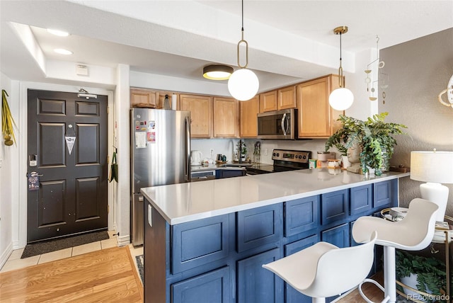 kitchen featuring decorative light fixtures, stainless steel appliances, a peninsula, light countertops, and light tile patterned floors