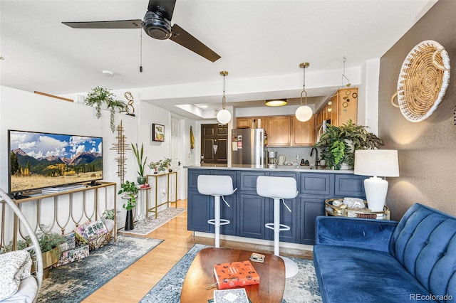 living room with light wood-style floors, baseboards, and a ceiling fan