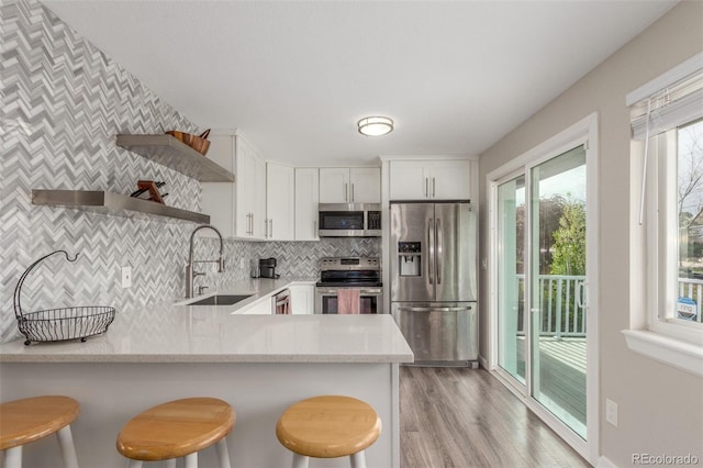 3841 W Quinn Pl, Denver, CO 80236 - kitchen with stainless steel appliances, open shelves, a peninsula, white cabinets, and tasteful backsplash