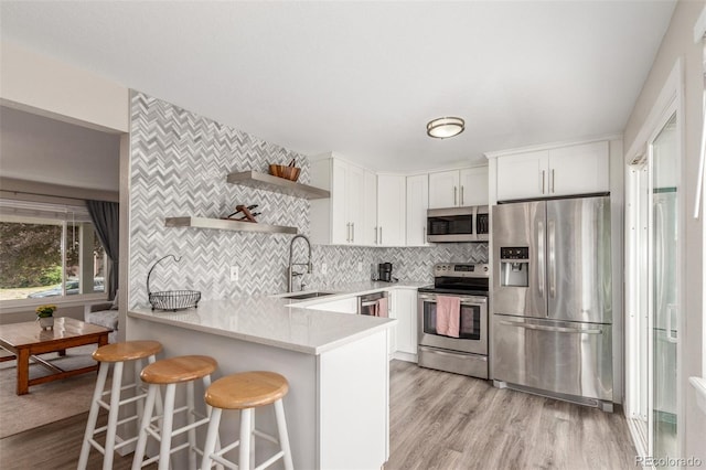 3841 W Quinn Pl, Denver, CO 80236 - kitchen with stainless steel appliances, open shelves, a peninsula, light countertops, and decorative backsplash