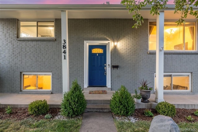 3841 W Quinn Pl, Denver, CO 80236 - doorway to property featuring covered porch and brick siding