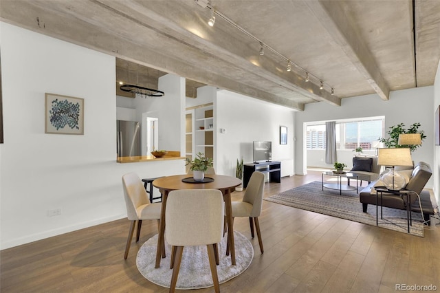 dining room featuring hardwood / wood-style floors, track lighting, baseboards, and beam ceiling