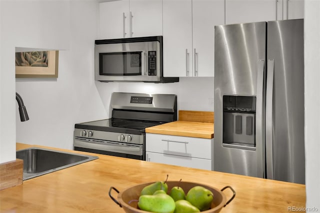 kitchen featuring a sink, stainless steel appliances, white cabinets, and butcher block counters